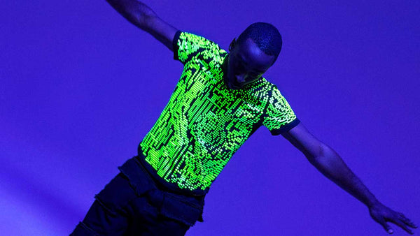 Model wearing neon green reflective Digital Glitch tee glowing under ultraviolet lighting.