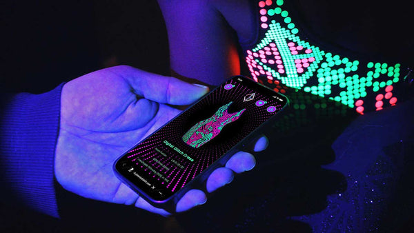 Smartphone displaying connected fashion NFC experience beside glowing Digital Glitch holographic garment.