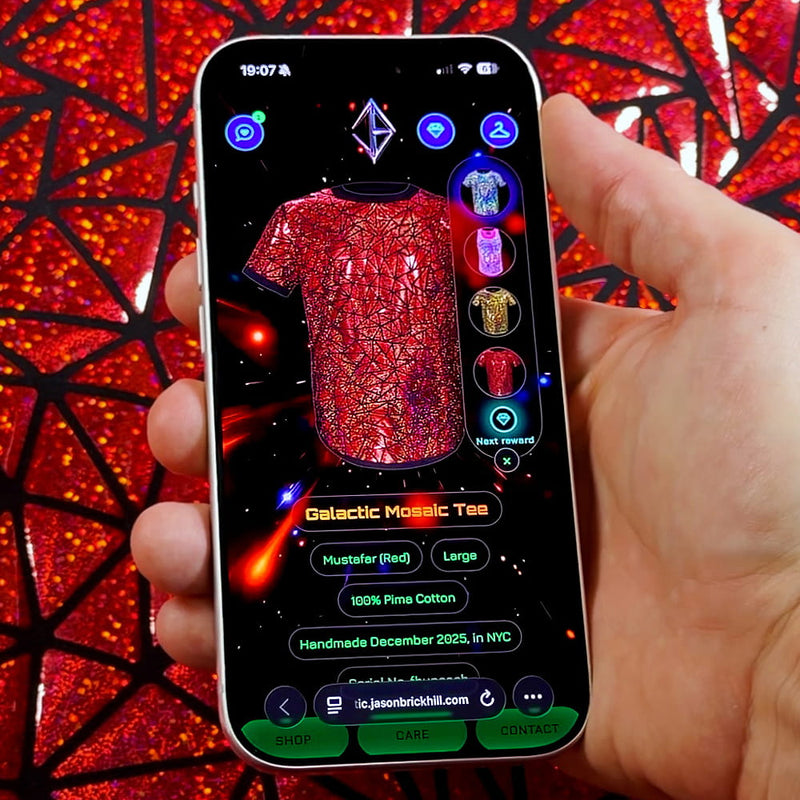 Hand holding a smartphone scanning a Jason Brickhill Galactic Mosaic Tee to activate the NFC digital experience.